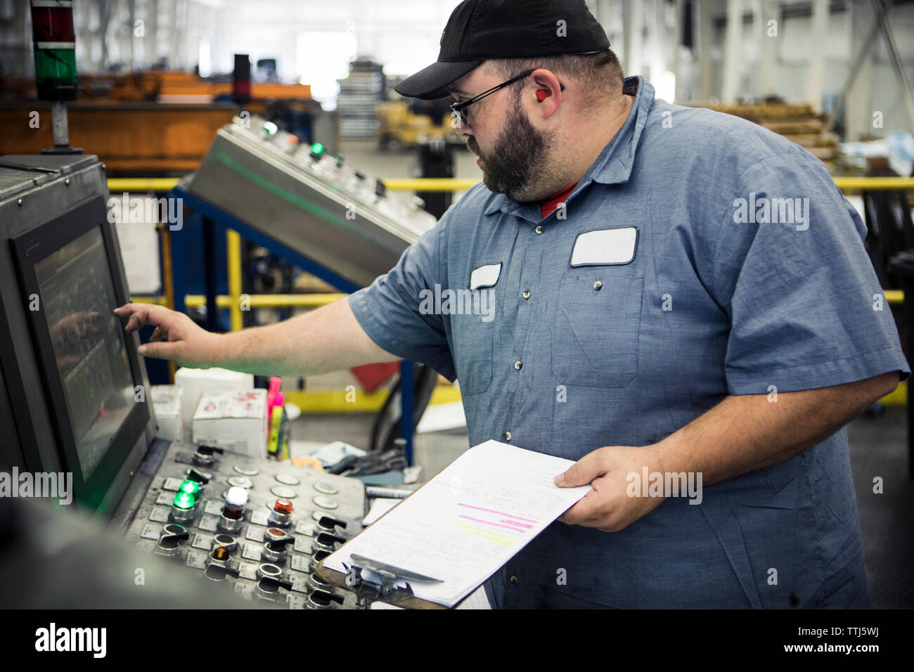 Il sovrappeso lavoratore manuale funzionamento di macchinari al pannello di controllo nella industria del metallo Foto Stock