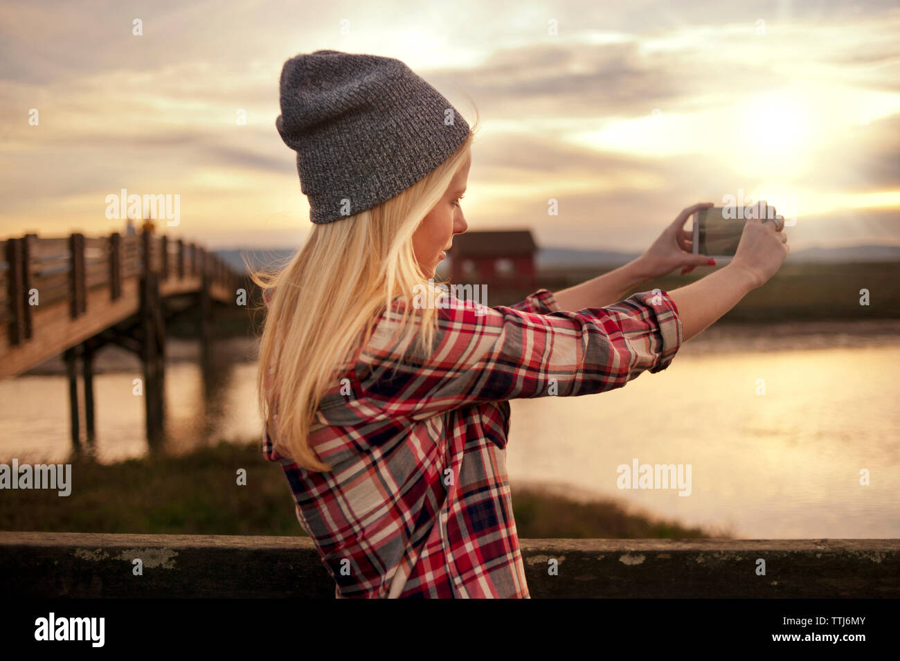 Donna fotografare con il telefono cellulare durante il tramonto Foto Stock