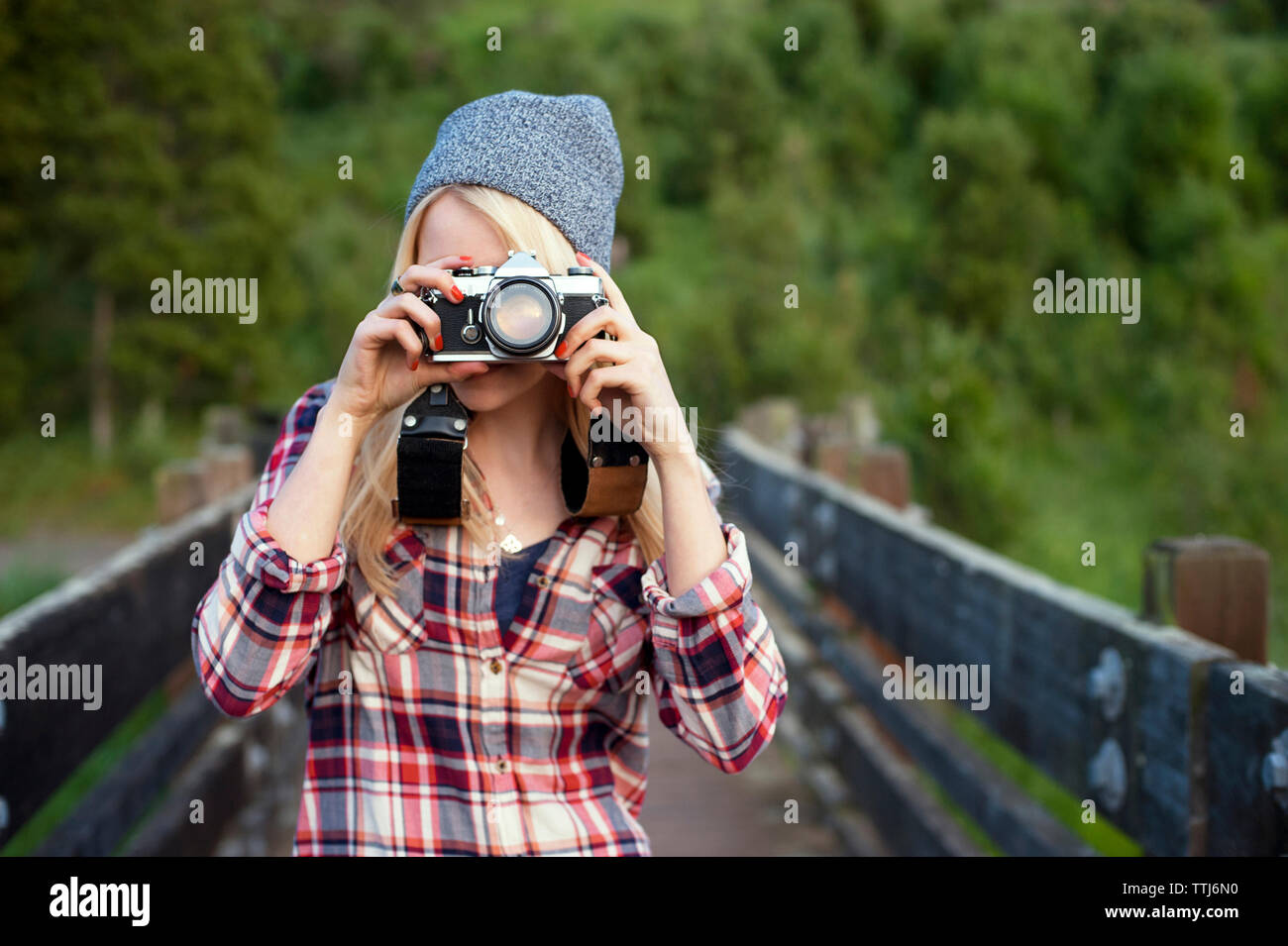 Donna di fotografare con la fotocamera mentre si sta in piedi sul ponte Foto Stock