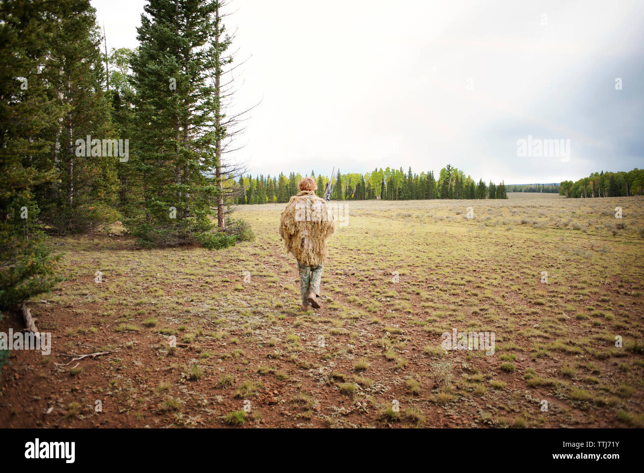 Uomo in Abbigliamento camouflage camminando sul campo Foto Stock