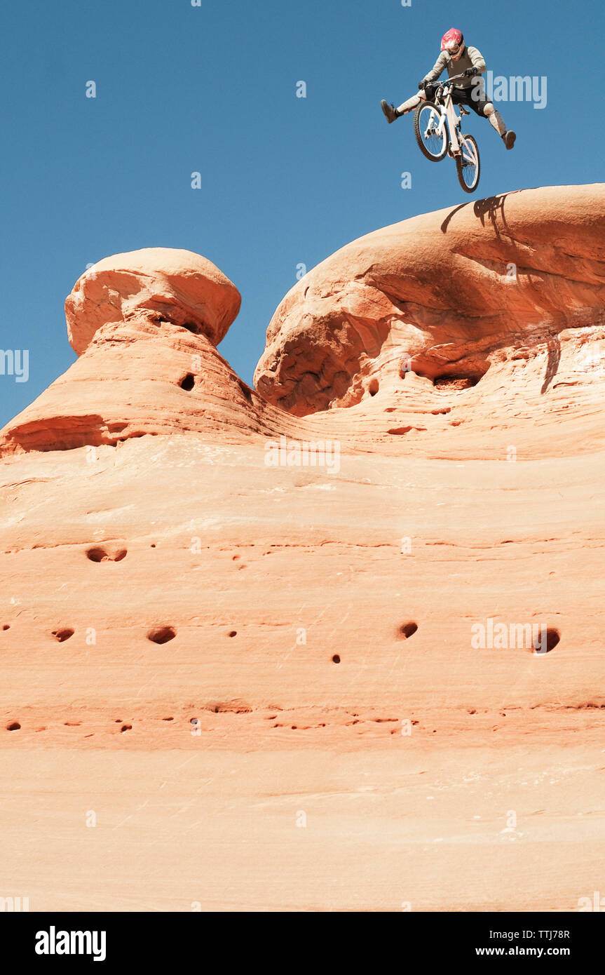 Basso angolo vista del ciclista saltando dal dirupo contro il cielo blu chiaro Foto Stock