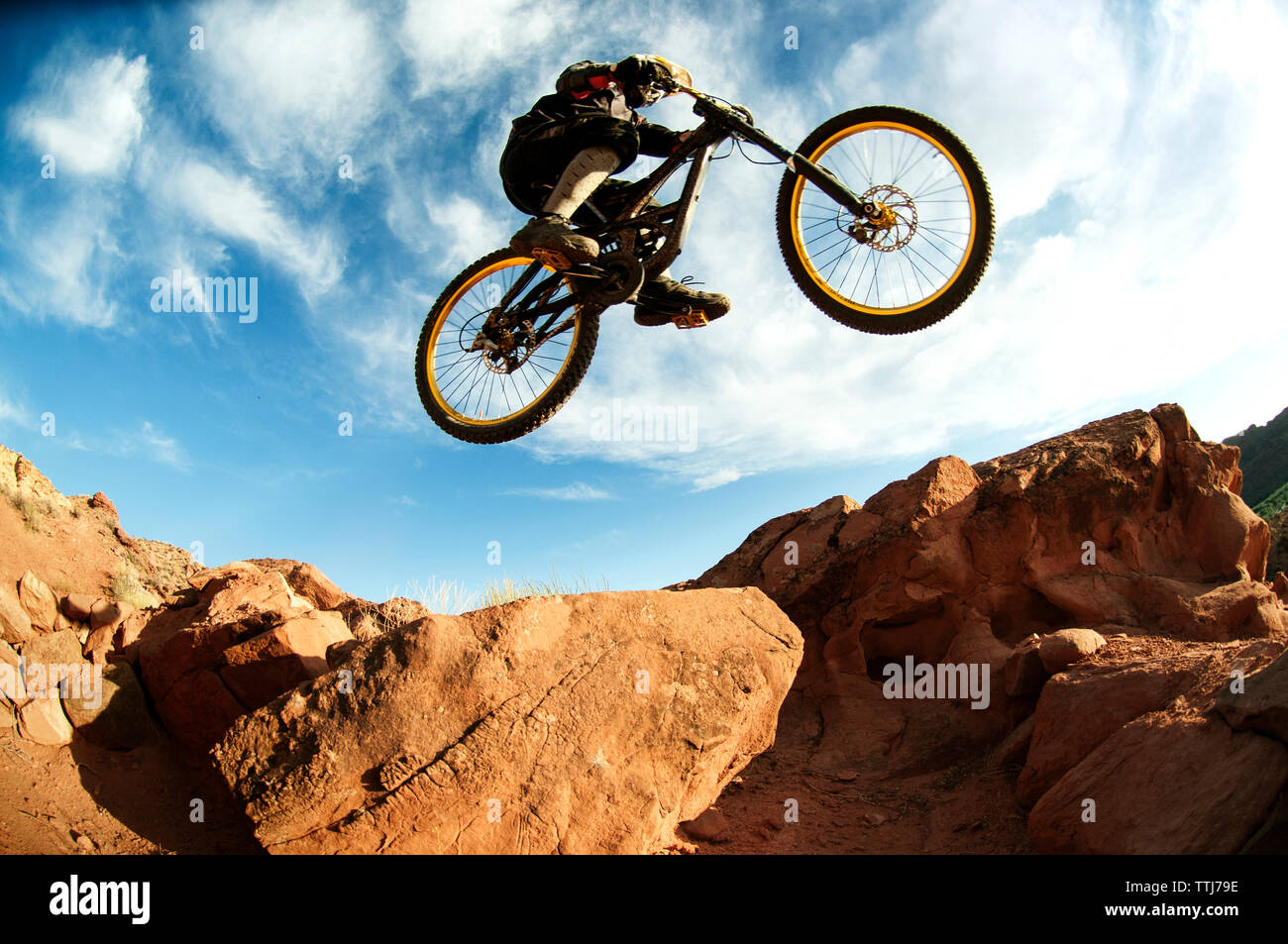 Mountain Biker eseguendo acrobazie a mezz aria contro sky Foto Stock
