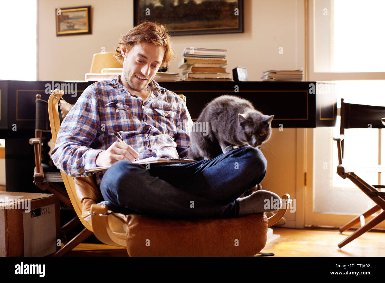Uomo con cat iscritto mentre è seduto sulla sedia a dondolo Foto Stock
