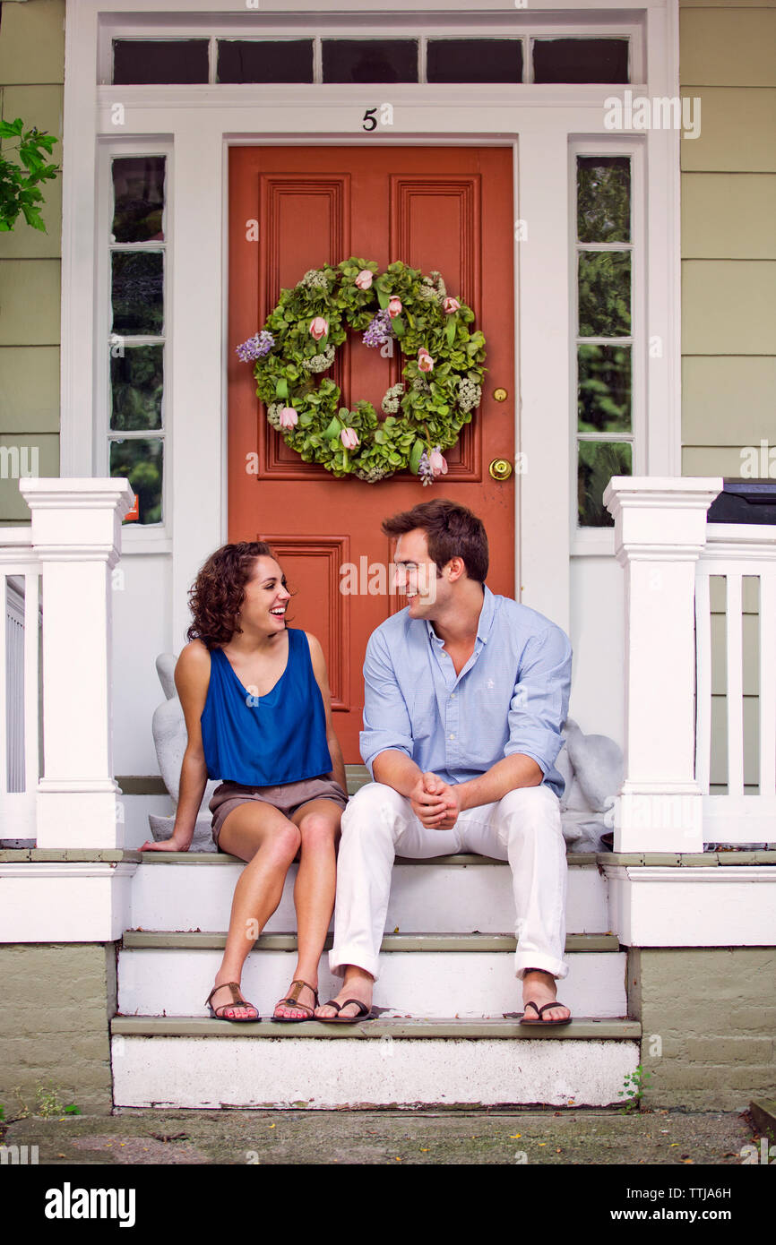 Coppia felice tenendo mentre è seduto sulla parte anteriore stoop Foto Stock