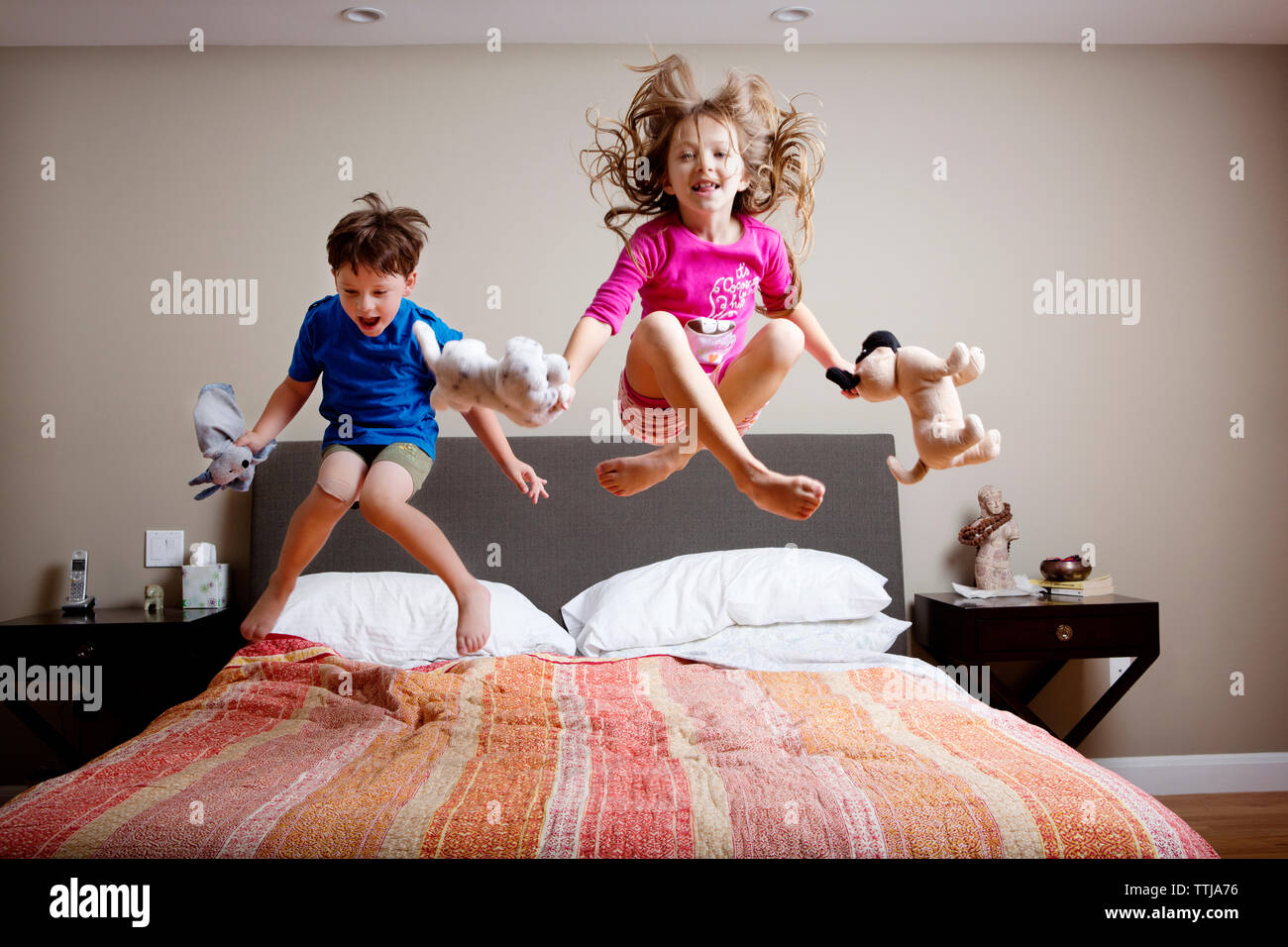 Giocoso i bambini di saltare sul letto di casa Foto stock - Alamy