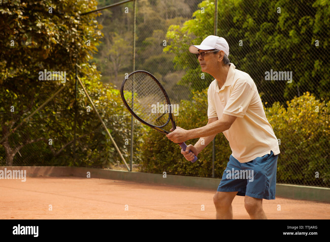 Senior uomo giocando a tennis a corte Foto Stock