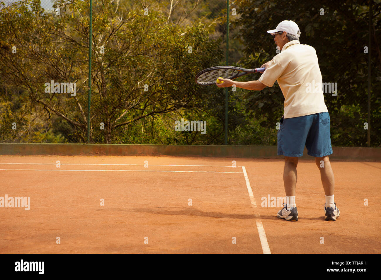 Vista posteriore dell'uomo gioca a tennis a corte Foto Stock
