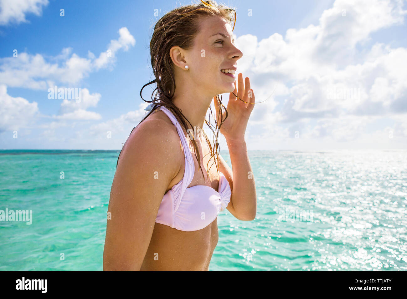 Donna felice in bikini top contro il cielo nuvoloso Foto Stock