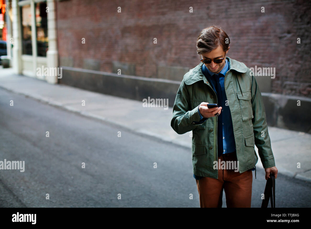 Uomo che utilizza il telefono cellulare mentre si sta in piedi in strada Foto Stock