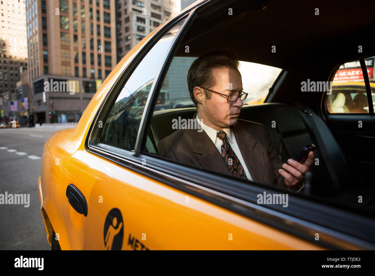 uomo d'affari che usa il telefono cellulare in taxi Foto Stock