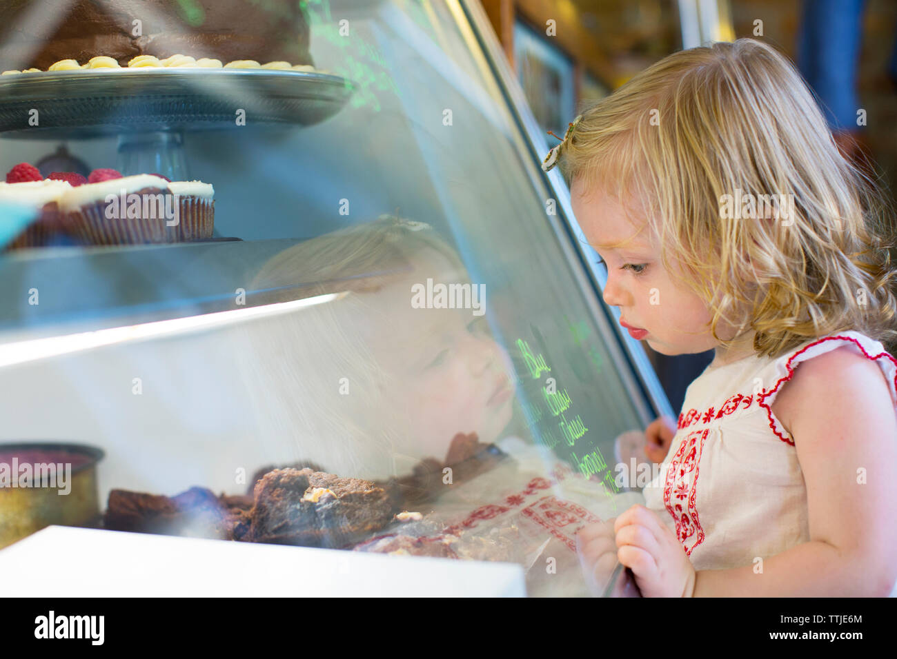 Baby girl guardando sweet food mantenuta a visualizzare in negozio Foto Stock