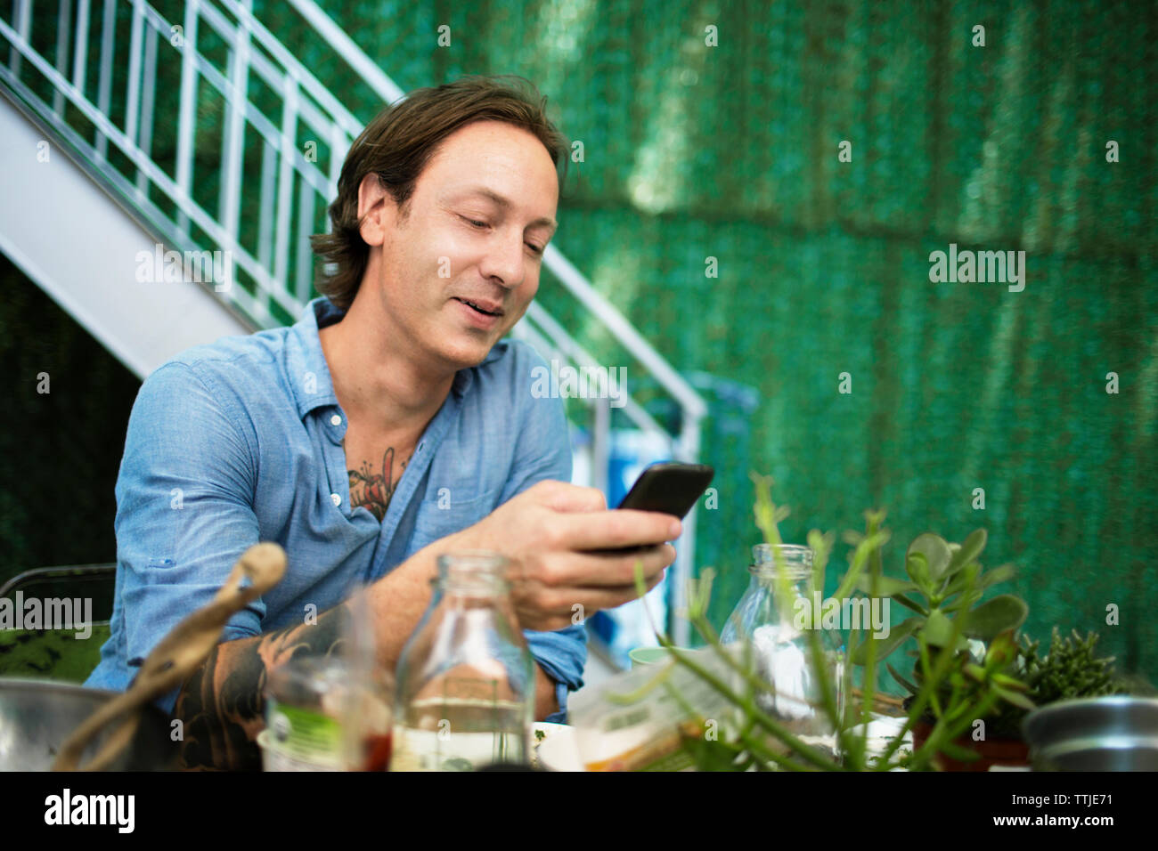 Uomo che guarda un telefono cellulare al cortile Foto Stock