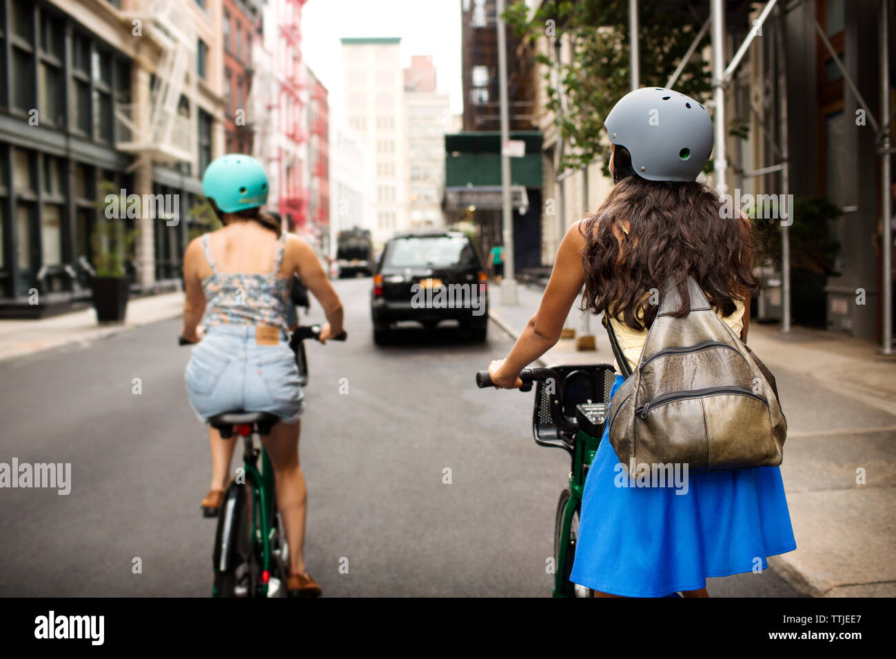 Vista posteriore di amici equitazione Bicicletta su una strada di città Foto Stock