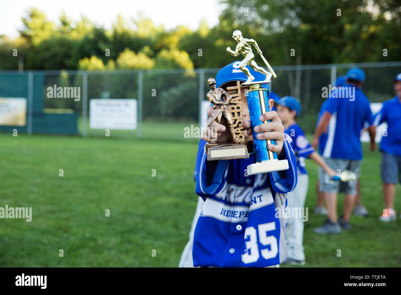 Ragazzo holding baseball trophy sul campo Foto Stock