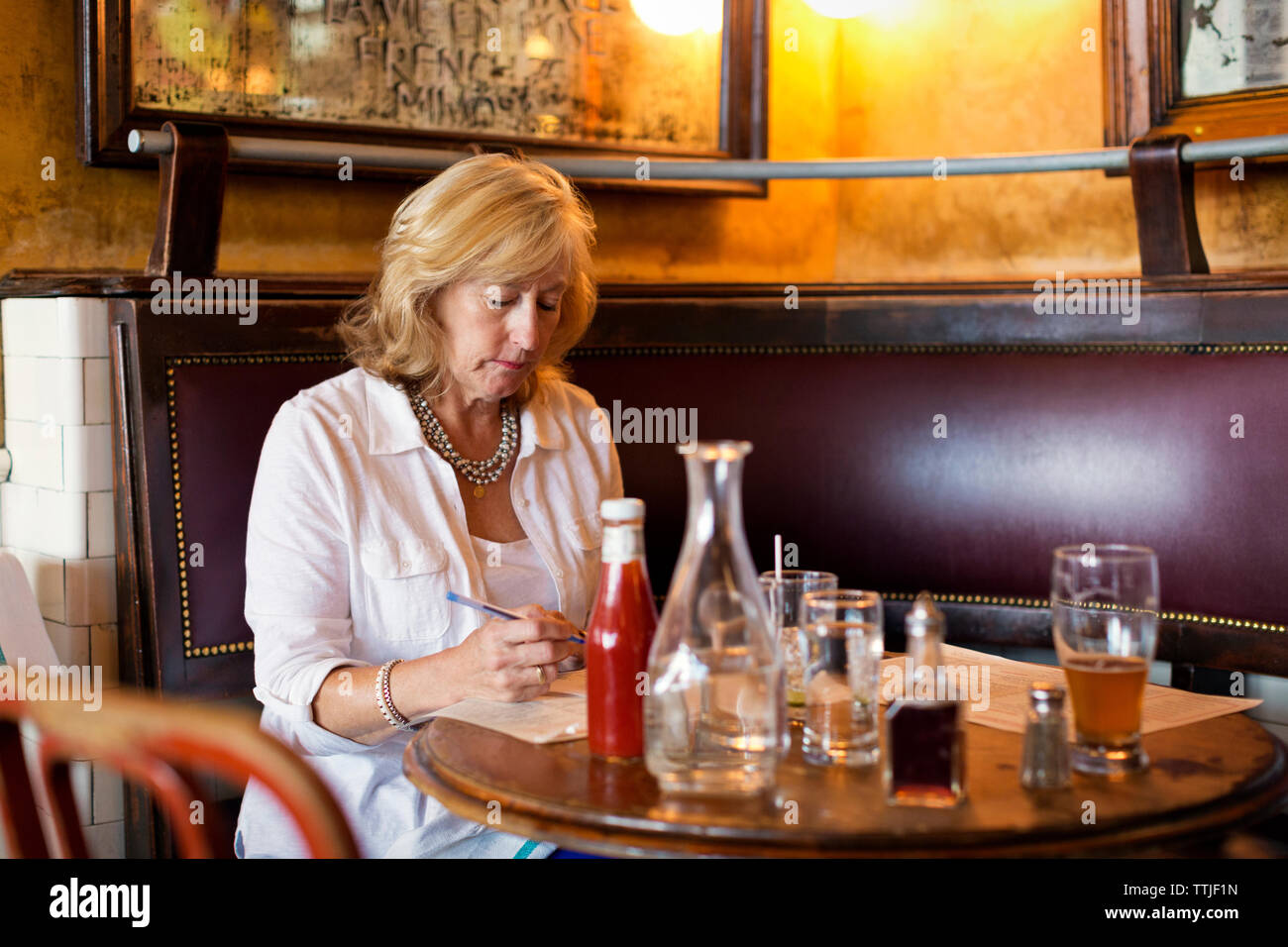 Donna tenendo la penna mentre è seduto al tavolo nel ristorante Foto Stock
