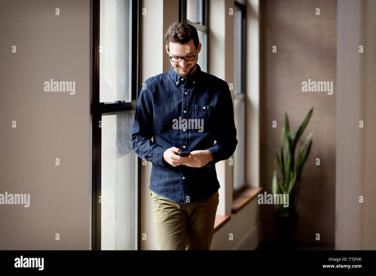 Uomo che utilizza il cellulare mentre in piedi a casa Foto Stock