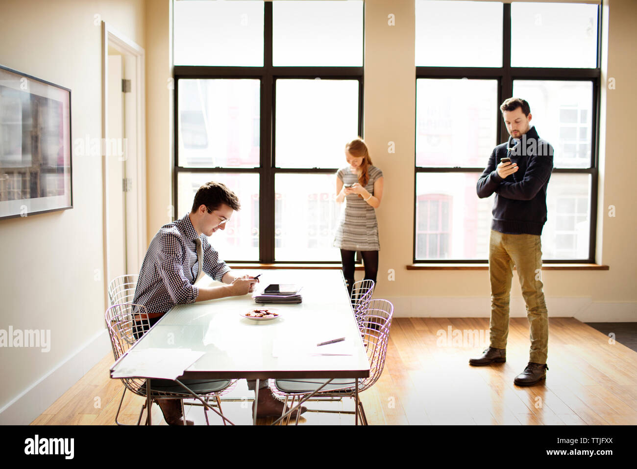 Gli amici utilizzando il telefono cellulare a casa Foto Stock