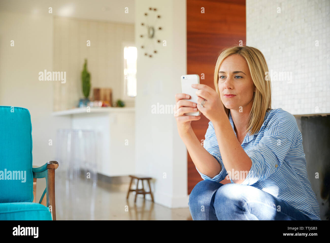 Donna che utilizza smart phone mentre è seduto a casa Foto Stock