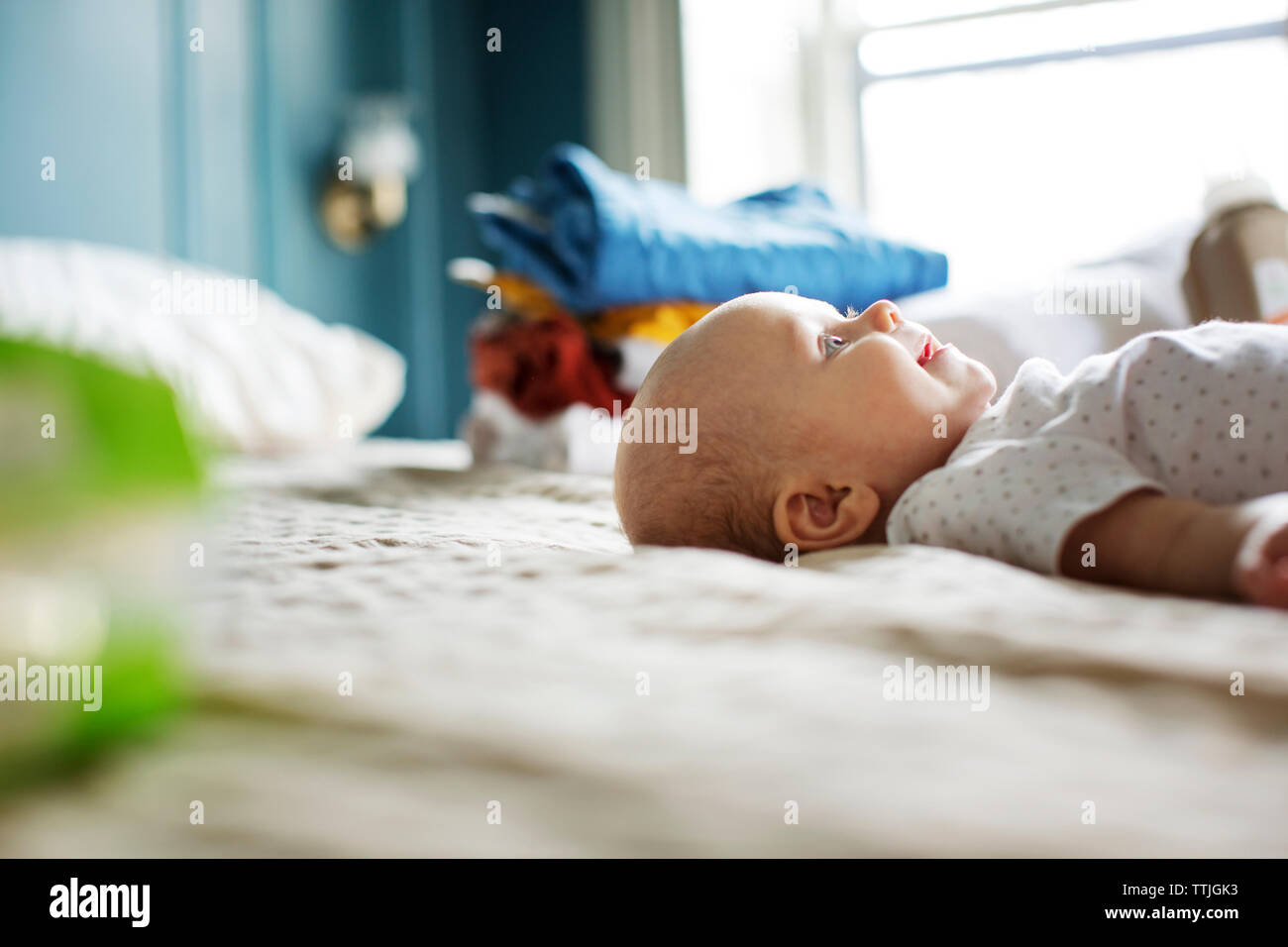 Il livello superficiale di happy Baby girl giacente sul letto Foto Stock