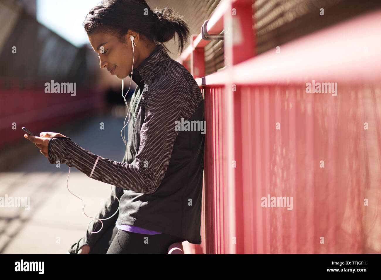 Donna ascoltare musica mentre appoggiata sulla recinzione al Williamsburg Bridge passaggio pedonale Foto Stock