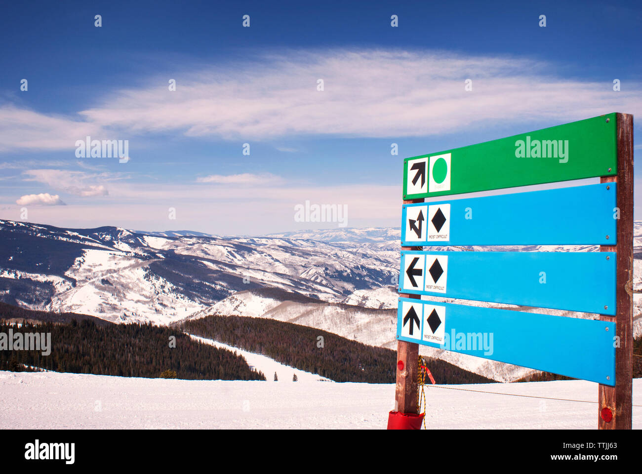 Segno direzionale di bordo su strade coperte di neve montagna contro sky Foto Stock