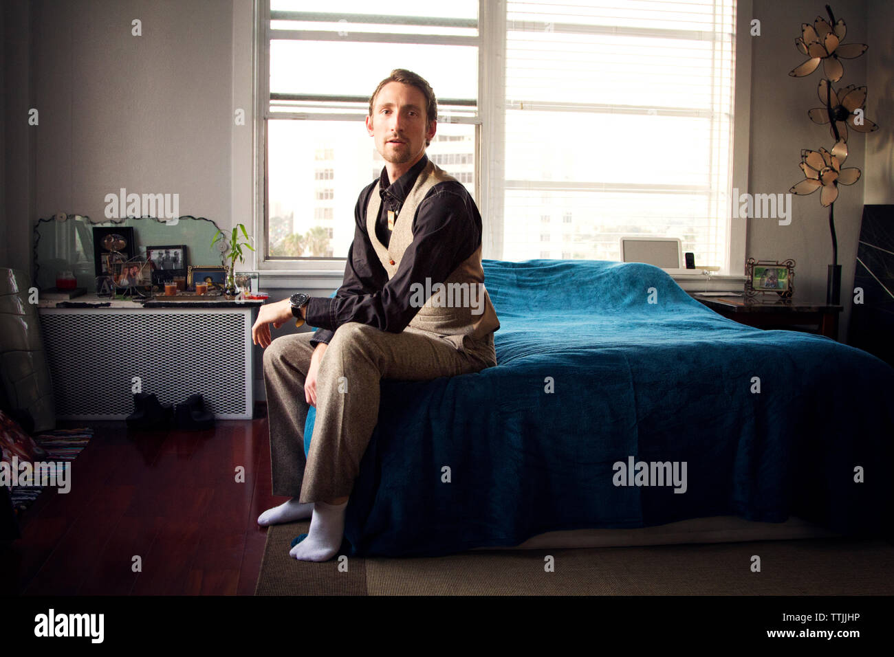 Ritratto di uomo seduto sul letto di casa Foto Stock