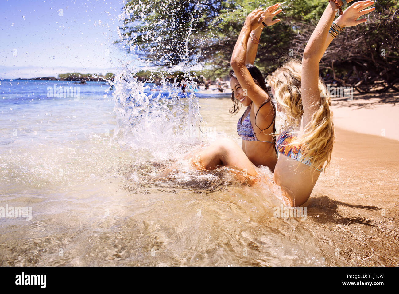 Gli amici gli spruzzi di acqua mentre è seduto alla riva Foto Stock