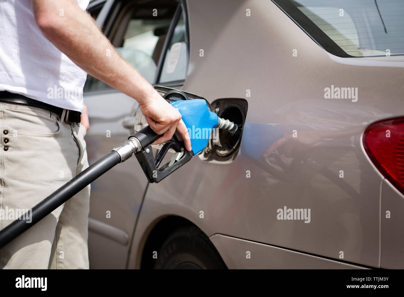 Sezione mediana uomo il rifornimento auto presso la stazione di gas Foto Stock