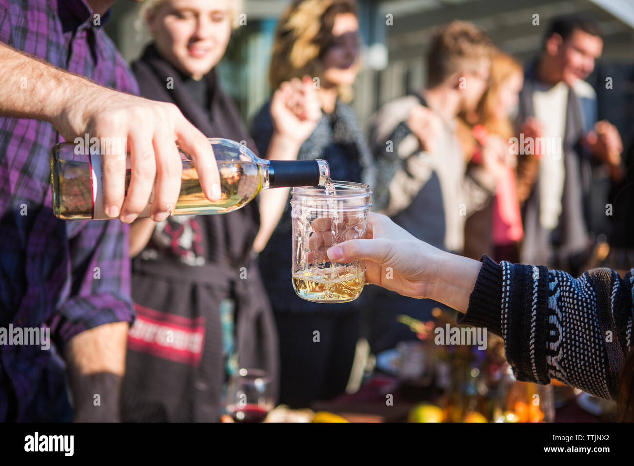 Immagine ritagliata dell uomo a versare birra per amico al party in giardino Foto Stock