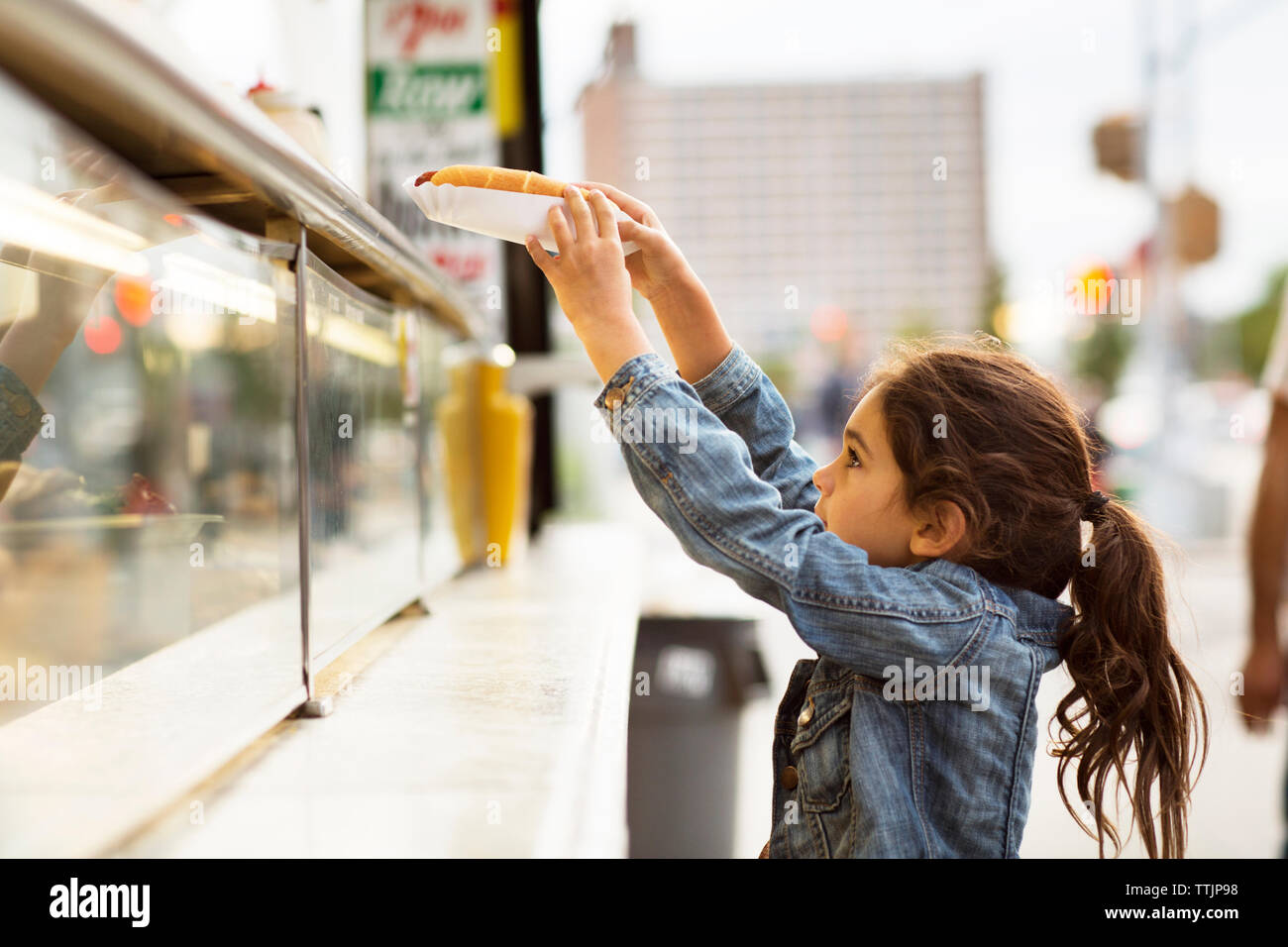 Ragazza tenendo hot dog dal cibo carrello Foto Stock