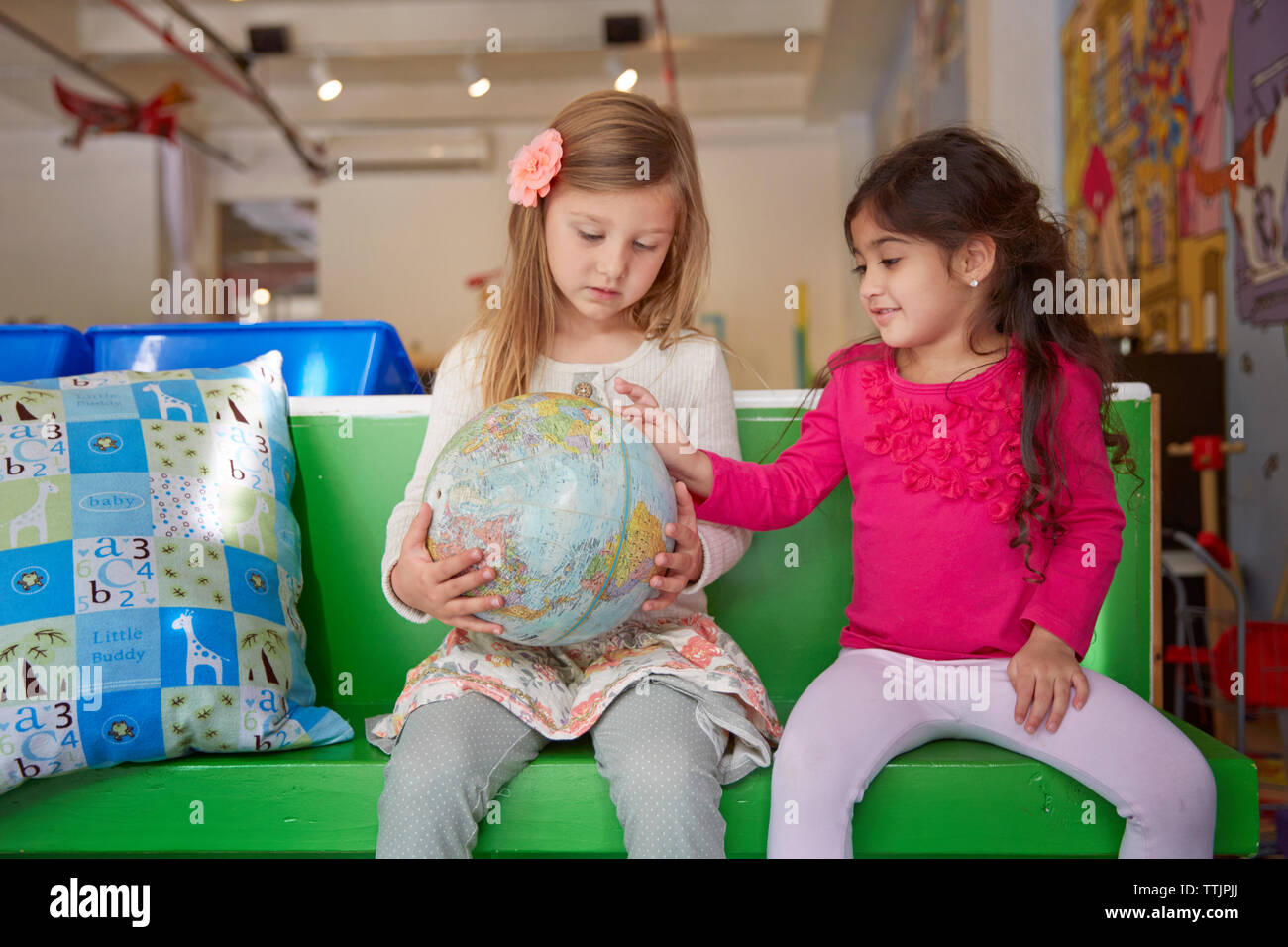 Ragazze guardando al mondo stando seduti sul sedile verde a cura del bambino Foto Stock