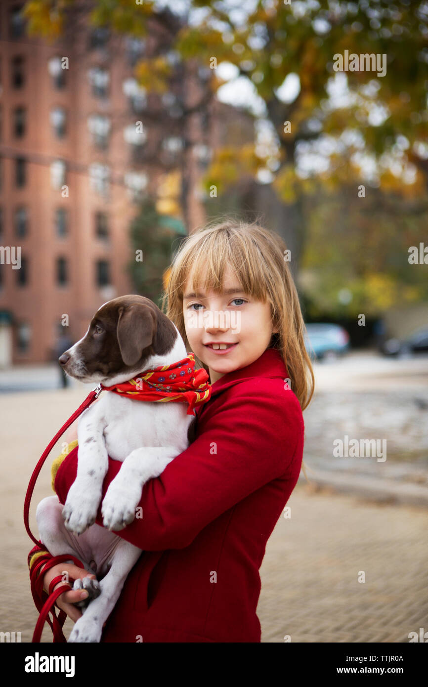 Ritratto di ragazza sorridente che trasportano il cane mentre si sta in piedi sul sentiero Foto Stock