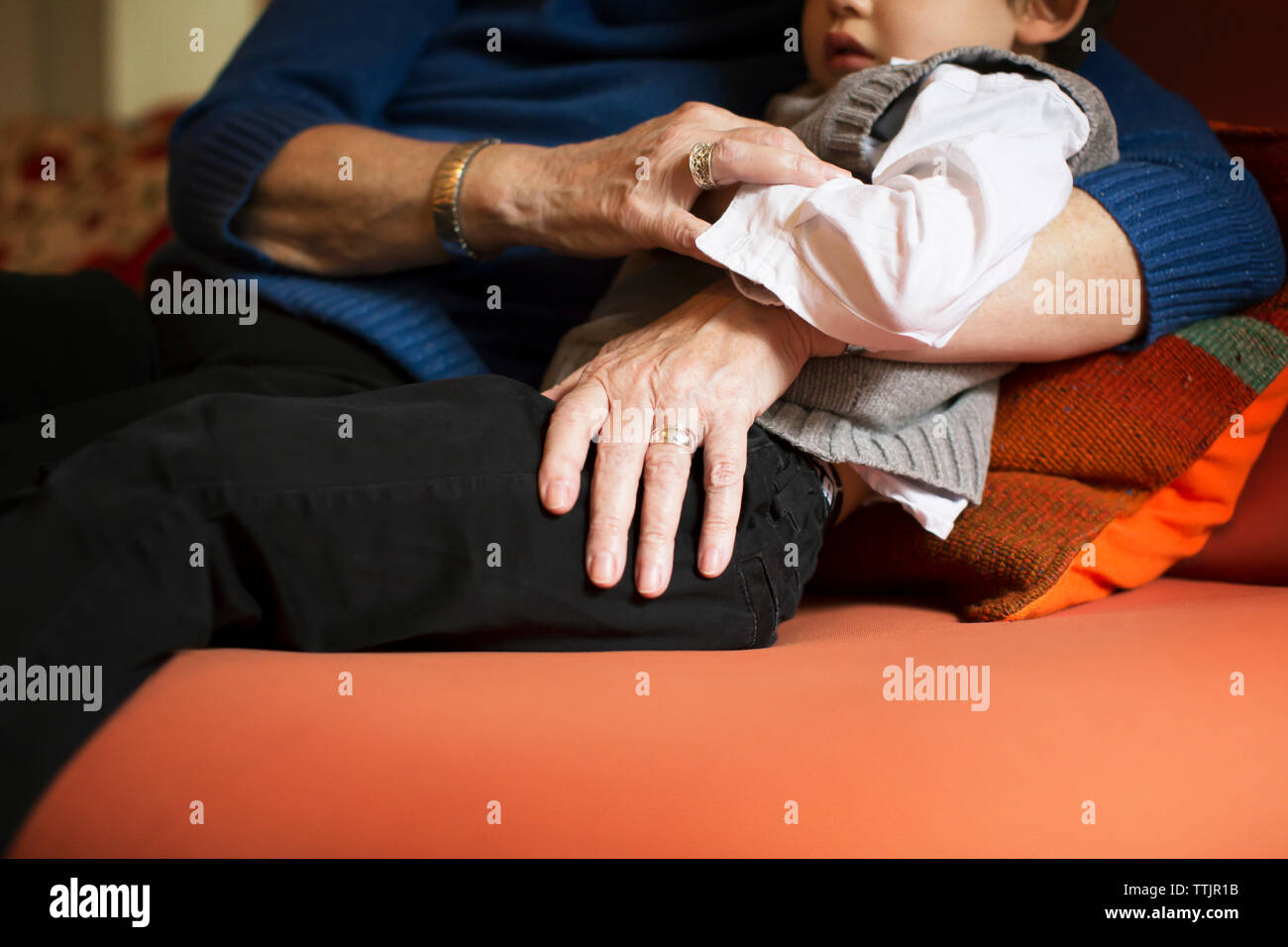 Sezione mediana della nonna abbracciando boy mentre vi rilassate sul divano di casa Foto Stock