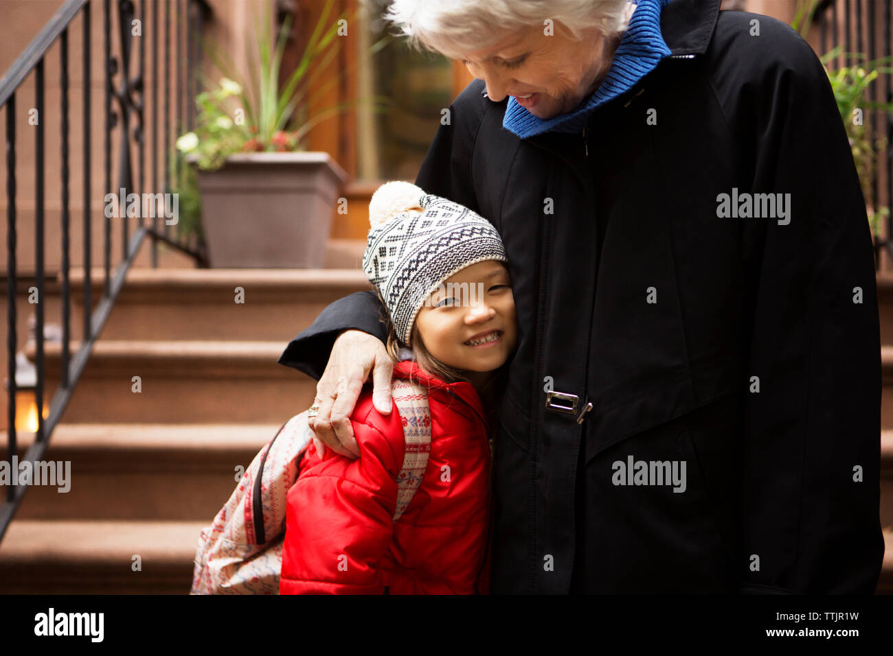 Ragazza sorridente mentre in piedi con la nonna su gradini Foto Stock