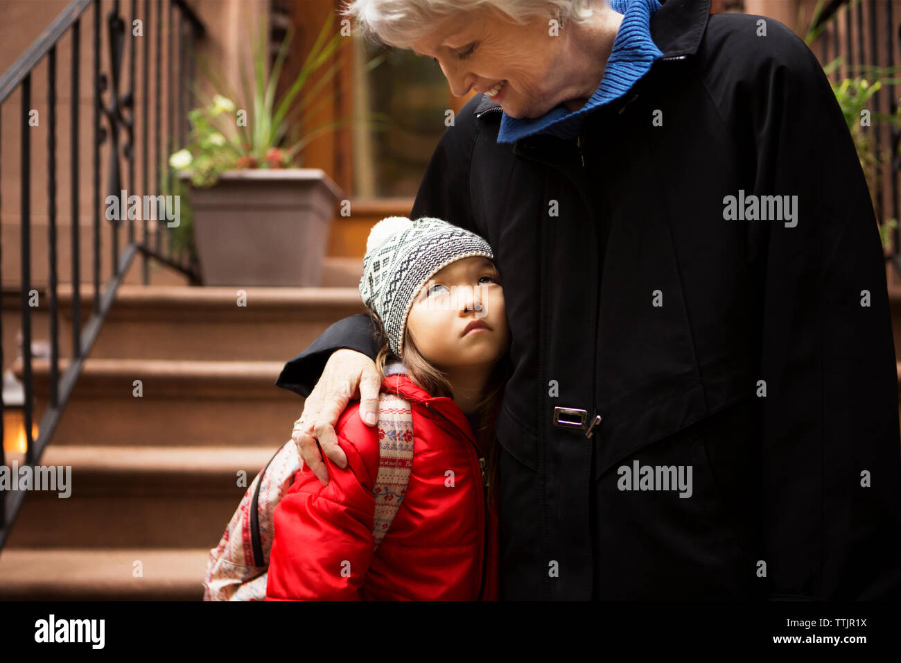 La nipote cercando la nonna stando in piedi sui gradini Foto Stock