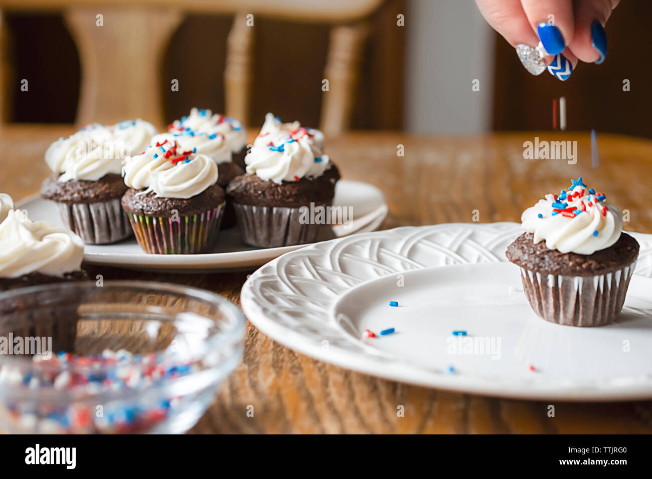 Il cioccolato mini cupcake sulla piastra bianca decorata con rosso, bianco e blu spruzza. Motion Blur di gocciolamento spruzza. Ulteriori tortine ho Foto Stock