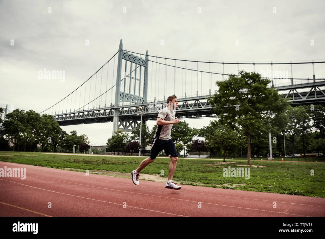 Vista laterale dell'uomo in esecuzione su sport via contro Triborough Bridge Foto Stock