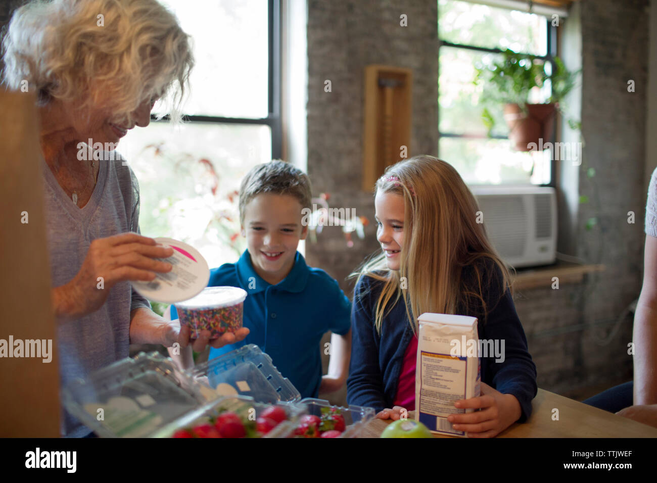 Bambini eccitato guardando la nonna rimuovere gli alimenti in cucina Foto Stock