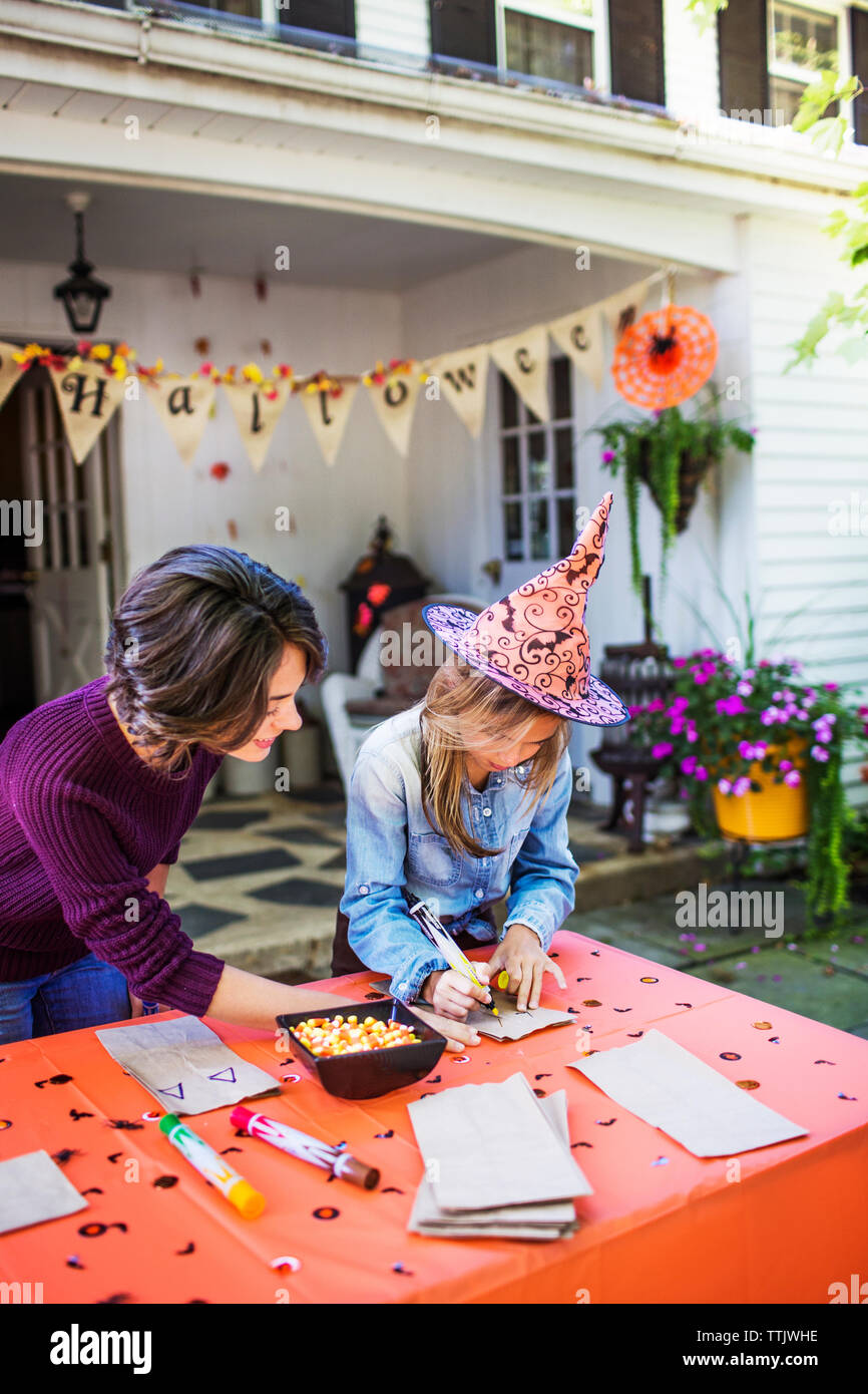 Madre figlia che assiste nella realizzazione di decorazione a tavola durante la festa di Halloween Foto Stock