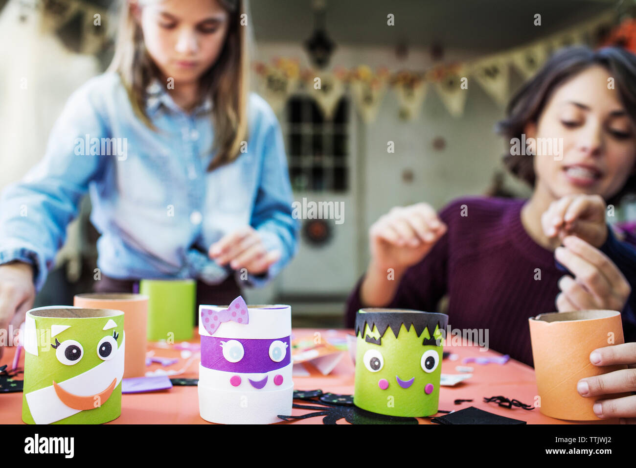 Madre facendo varie decorazione con i bambini a tavola durante la festa di Halloween Foto Stock