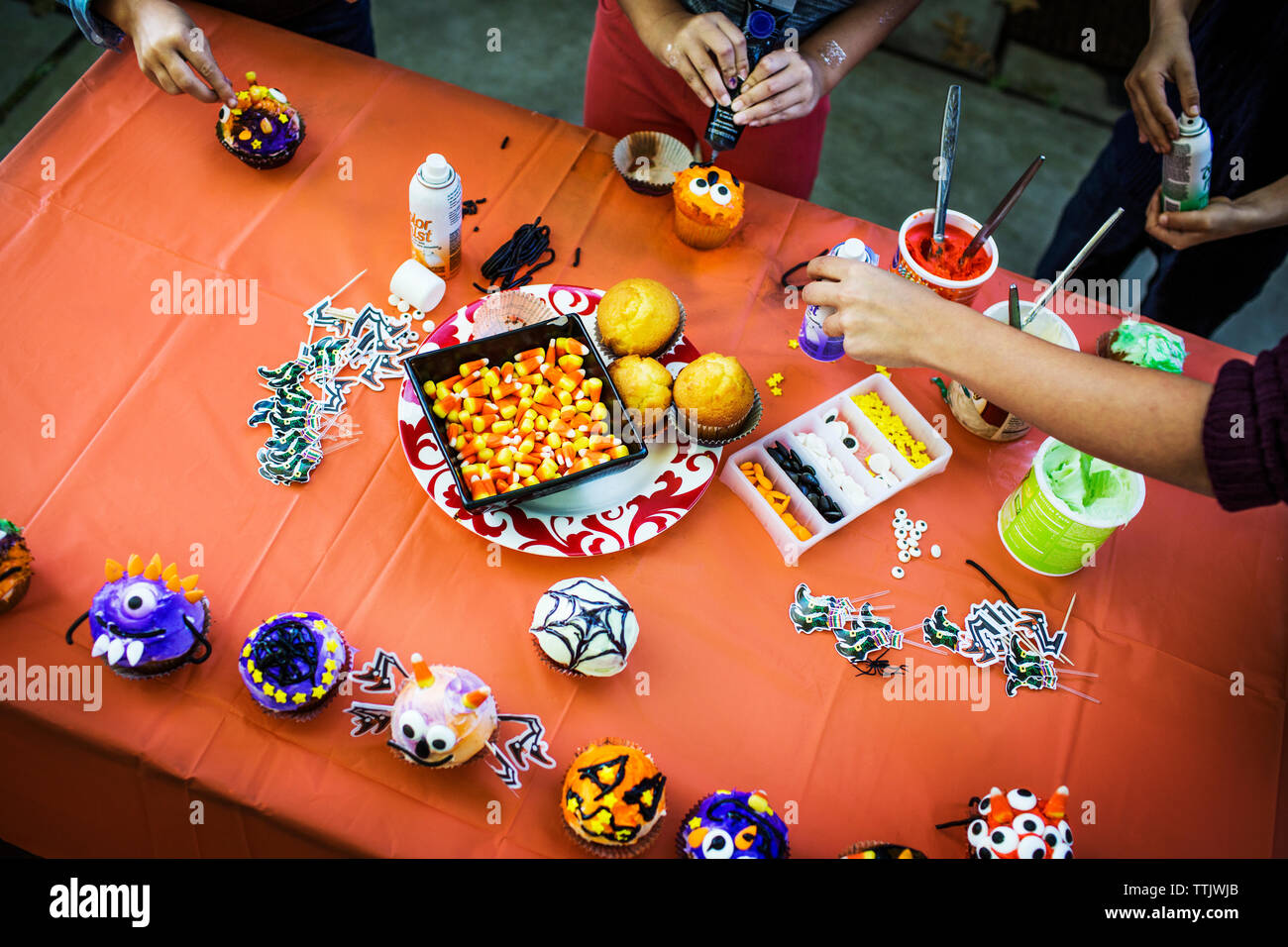 Madre e bambini decorare i muffin al tavolo durante la festa di Halloween Foto Stock
