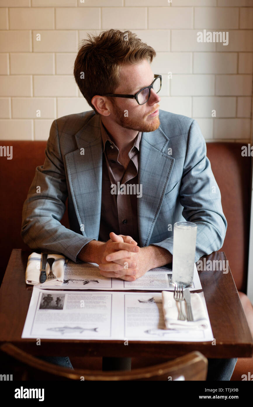 Considerato l uomo che guarda lontano mentre è seduto al tavolo nel ristorante Foto Stock