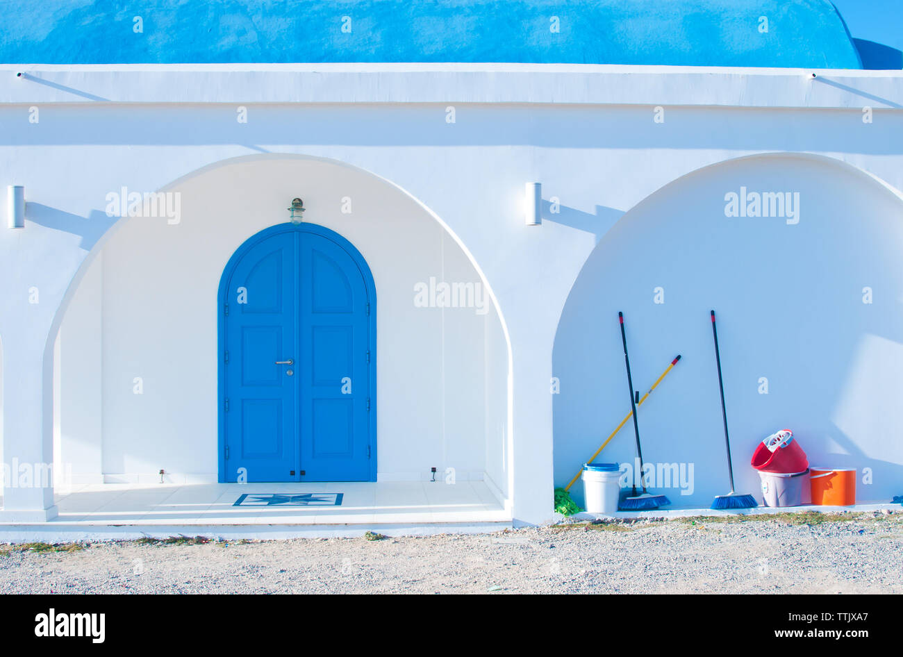 Ayia Thekla Cappella blu con porte ad arco e colonne nei pressi di Agia Napa, Cipro. Molti scope e tazze colorate in piedi vicino alla parete. Giornata calda in fal Foto Stock