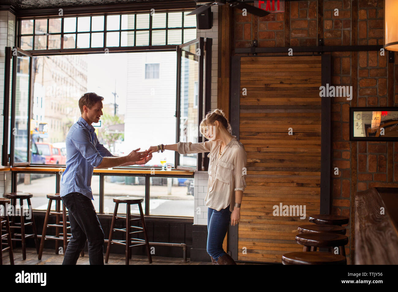 Man mano tesa della donna in piedi in bar Foto Stock