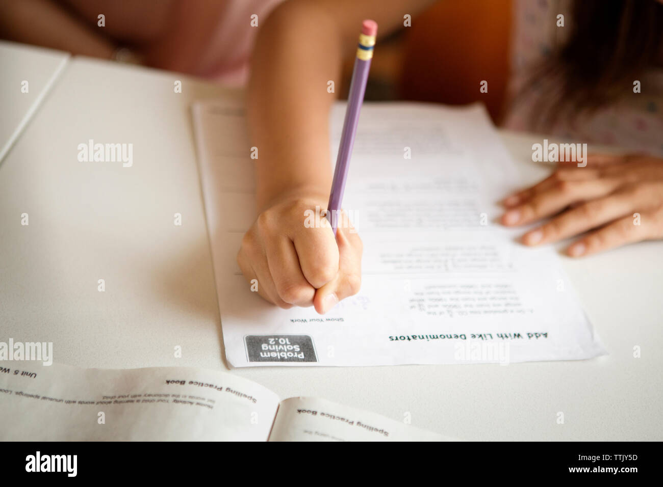 Immagine ritagliata della ragazza che studiano a tavola Foto Stock