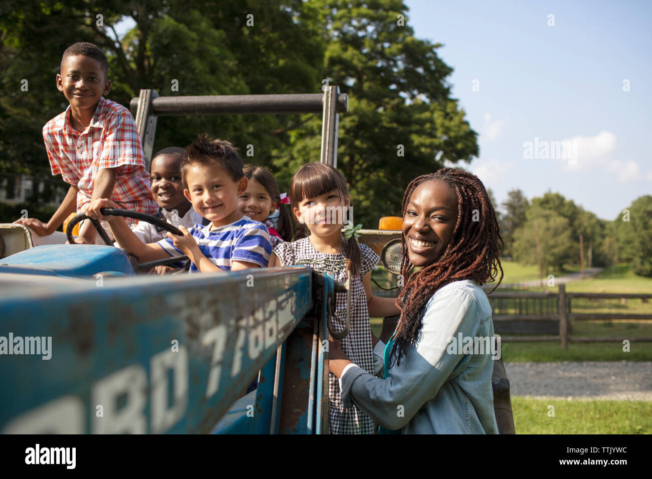 Ritratto di insegnante con i bambini con il trattore sul campo Foto Stock