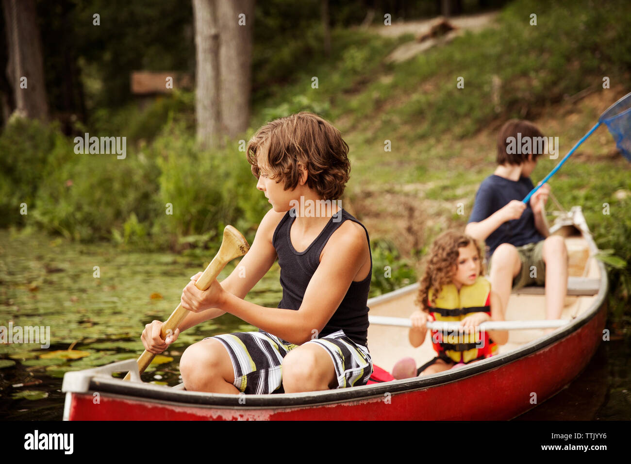 Bambini oaring seduti in canoa Foto Stock