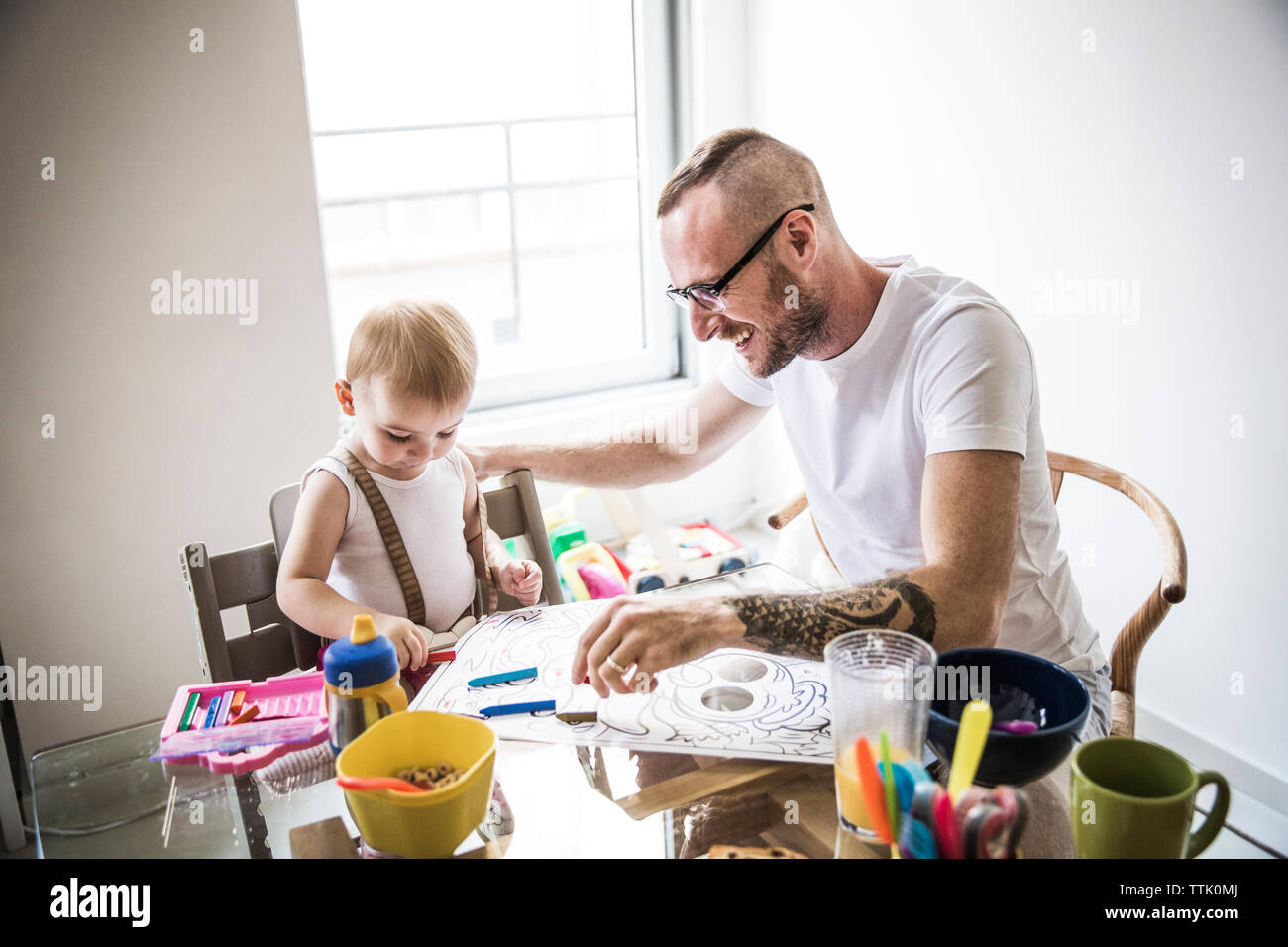 Padre sorridente disegno con la figlia mentre con la colazione a tavola Foto Stock