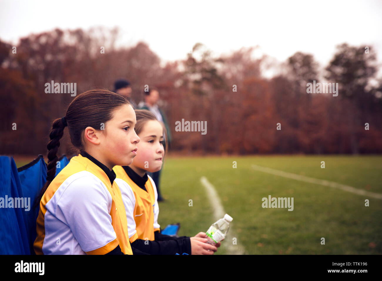 Amici indossando sport appoggio uniforme sulla sedia al campo di calcio Foto Stock