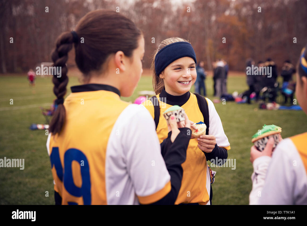 Felici i giocatori di calcio godendo i tortini al campo da gioco Foto Stock